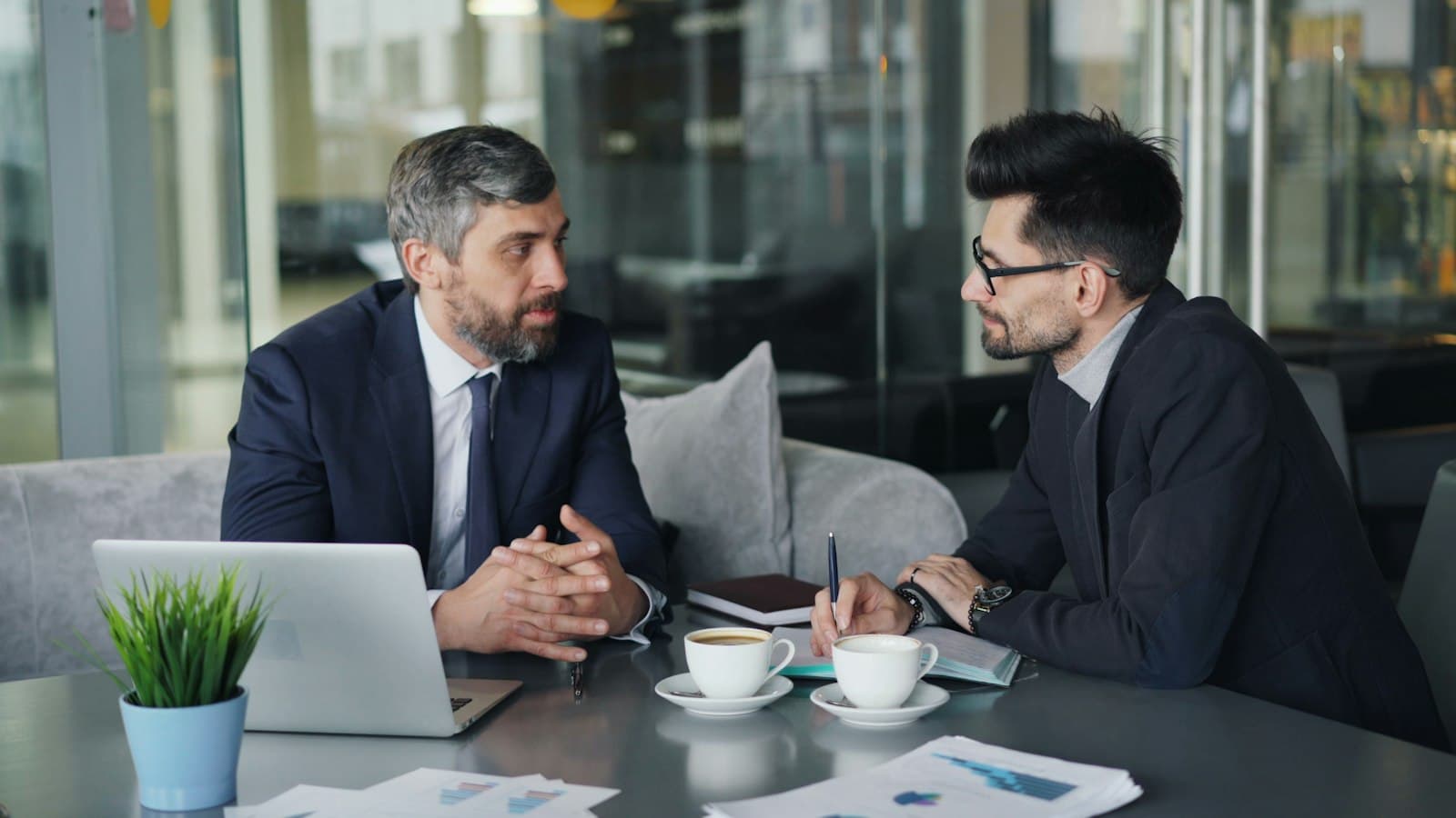 An executive and his operations partner reviewing priorities over a laptop